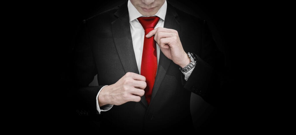 businessman-black-suit-tying-red-necktie